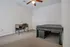 Bright and spacious bedroom with cozy carpet, featuring a minimalist desk and comfortable bed under a stylish ceiling fan.