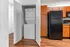 Modern apartment kitchen with sleek black appliances, abundant wooden cabinetry, and an in-unit washer and dryer for convenience.