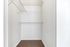 Spacious walk-in closet with white walls and carpeted floor, featuring sleek wire shelving for organized storage.