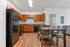 Modern kitchen with sleek black appliances, wooden cabinetry, and elegant dining area on stylish wooden flooring.
