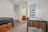 Bright bedroom with modern desk, sleek black chair, and ample natural light, adjacent to a bathroom with warm wood accents.