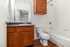 Bright and modern bathroom featuring elegant wood cabinets, sleek granite countertop, and pristine white fixtures for a contemporary feel.
