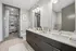 Sleek modern bathroom featuring a double vanity, large mirror, and walk-in closet with ample shelving space.