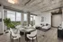 Modern apartment interior with open-plan living and dining area, featuring floor-to-ceiling windows offering stunning views, sleek furnishings, and industrial-style ceiling.