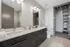 Luxurious bathroom with elegant double vanity, sleek cabinetry, and a stylish mirror, leading to a spacious closet area.