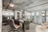 Modern loft apartment with sleek industrial design, featuring large windows, a stylish home office setup, and an open-concept kitchen with chic cabinetry.