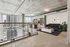 Modern loft apartment with sleek industrial design, featuring large windows with city views, a cozy living area with black leather sofa, and stylish decor in an open floor plan.