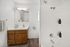 Contemporary bathroom with wooden vanity, mirror, and tub with modern fixtures.