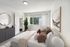 Stylish bedroom with modern decor, featuring a large window, cozy bed, and elegant artwork.