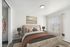 Modern bedroom with plush beige bed, stylish pillows, and elegant nightstands in a bright room.