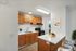 Modern kitchen with wooden cabinetry, sleek countertops, and natural lighting.