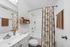 Bright modern bathroom with patterned shower curtain and stylish shelving.