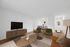 Chic living room with modern furnishings, TV setup, and dining area in an open-concept apartment.