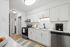 Contemporary kitchen with stainless steel appliances, white cabinetry, and marble countertops.