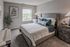 Elegant bedroom with a grey upholstered bed, plush pillows, and a scenic window view.