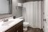 Sleek bathroom with dark wood vanity, modern faucet, and white shower curtain.