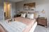Inviting bedroom with elegant decor, featuring a plush bed, warm lighting, and abstract artwork.