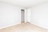 Spacious, sunlit bedroom with beige carpet and an open closet.