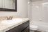 Modern bathroom with sleek countertop, sink, and bathtub adorned with glossy tiles.