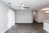 Spacious living room with sleek ceiling fan, wood-style flooring, and light-filled atmosphere.
