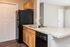 Sleek kitchen with granite countertops, modern sink, and dark refrigerator.