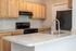 Modern kitchen with light wooden cabinets, granite countertops, and stainless steel appliances.