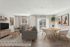 Modern living and dining area with stylish gray furniture, chic wall art, and natural light streaming through large windows.