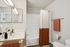 Elegant bathroom featuring a modern sink, stylish lighting, and a vibrant orange accented shower curtain for a cozy, inviting feel.