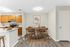 Chic dining area with modern wooden table and chairs beside a stylish kitchen featuring warm wood cabinets and sleek countertops.