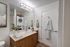 Contemporary bathroom with stacked washer and dryer, stylish wood cabinetry, and modern fixtures.