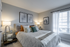 Elegant bedroom with cozy lighting, modern artwork, and stylish neutral tones, featuring a plush bed, framed art pieces, and large window with soft curtains.