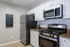 Modern kitchen with sleek stainless steel appliances, granite countertops, and a wall-mounted menu board for a chic touch.