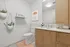 Modern bathroom with light wood cabinetry, elegant fixtures, and decorative elements, including hanging plants and minimalistic artwork.