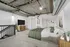 Modern loft-style bedroom with industrial ceiling, cozy green bedding, large TV, and stylish decor.
