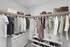 Spacious walk-in closet with neatly organized clothing and shoes, featuring an elegant blend of casual and formal wear on wooden hangers.