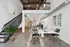 Modern industrial loft with high ceilings, open workspace, and mezzanine level, featuring sleek office furniture and artistic decor.