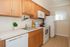 Bright, modern kitchen with sleek wooden cabinets, stainless steel appliances, and charming decor.