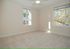 Bright and airy bedroom with plush carpet, large windows, and a ceiling fan, offering serene outdoor views.
