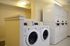 Pristine apartment laundry room featuring modern washers and dryers, illuminated by stylish overhead lighting.