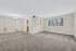 Bright and spacious living area with plush carpeting, large window offering scenic views, and elegant lighting fixture.