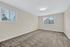 Spacious and cozy bedroom with plush carpet, large windows offering natural light, and a sleek ceiling light fixture.