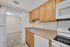 Bright and inviting kitchen with natural wood cabinets, modern appliances, and a spacious countertop, opening into a cozy living area.