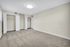 Spacious bedroom with plush carpeting and dual closets, illuminated by modern ceiling light. Perfectly neutral palette for personal touch.