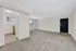 Spacious living area with plush carpeting, ample natural light, and a view into a bright kitchen with modern appliances.
