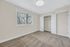 Bright, clean bedroom with cozy carpeting, large window, and open closet space, perfect for relaxation.