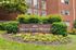 Charming Manchester Manor entrance with vibrant flower garden and lush greenery against brick facade.