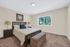Inviting bedroom with plush carpeting, elegant wooden bed frame, and natural light from a large window offering serene views.