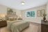 Inviting bedroom with plush bedding, elegant decor, and large window offering a serene outdoor view.