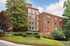 Charming Manchester Manor apartment building set amidst lush greenery with modern brick architecture and large windows.