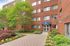 Inviting Manchester Manor entrance surrounded by vibrant flowers and lush greenery, highlighting a charming brick architecture.